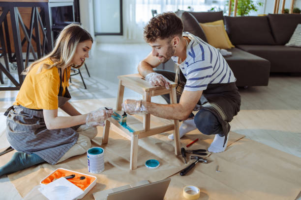 A young couple is painting wooden furniture in the living room